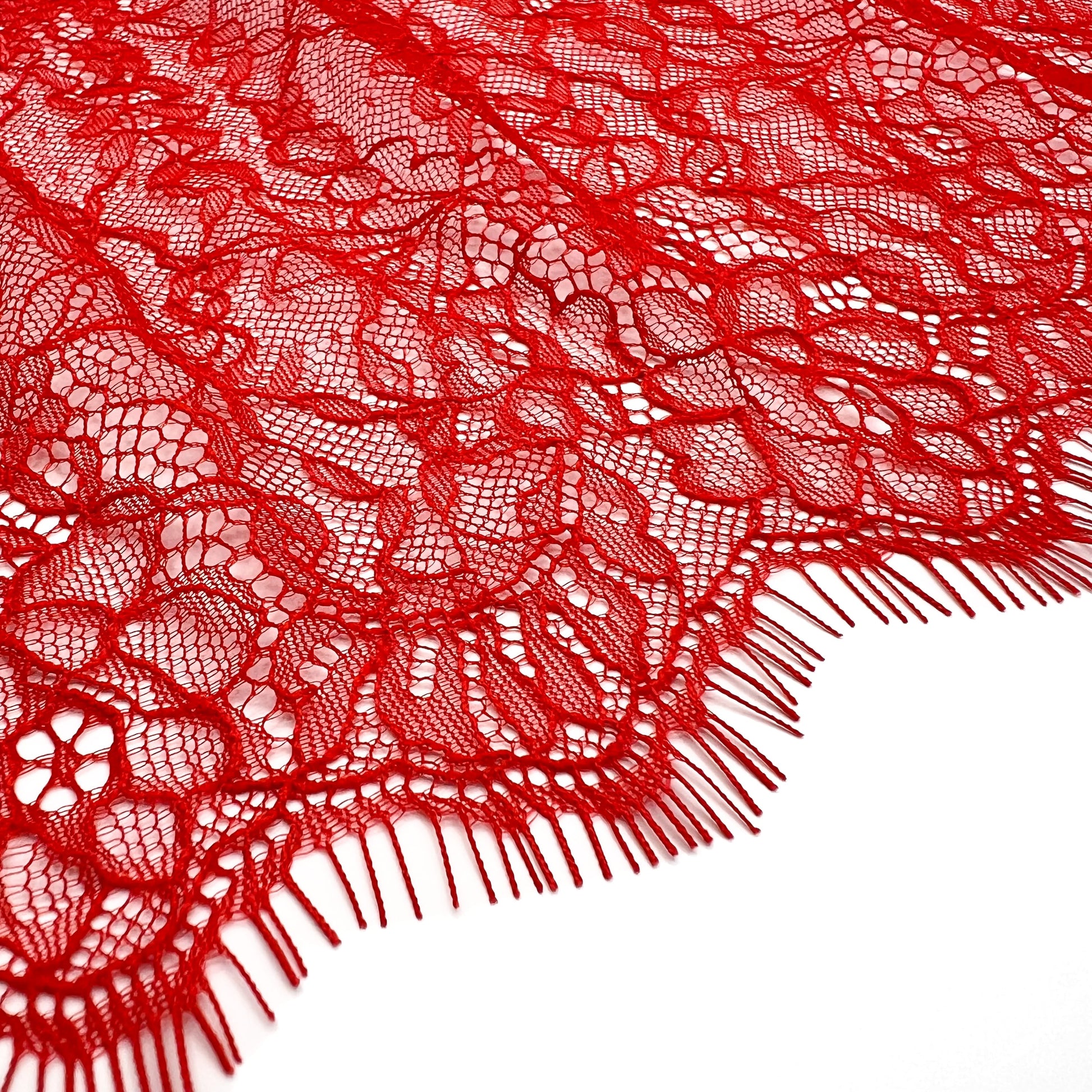 Close-up of red Chantilly lace showcasing its delicate floral texture and scalloped edges, designed for lingerie and decorative trims.