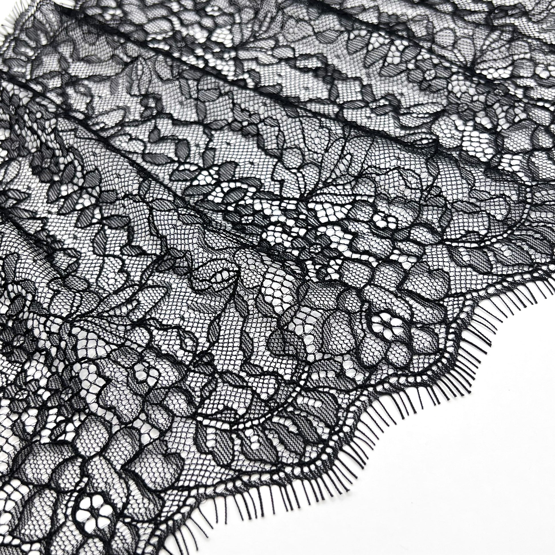 Folded black Chantilly lace with detailed floral patterns, 22 cm width, suitable for lingerie, accessories, and garment decoration.