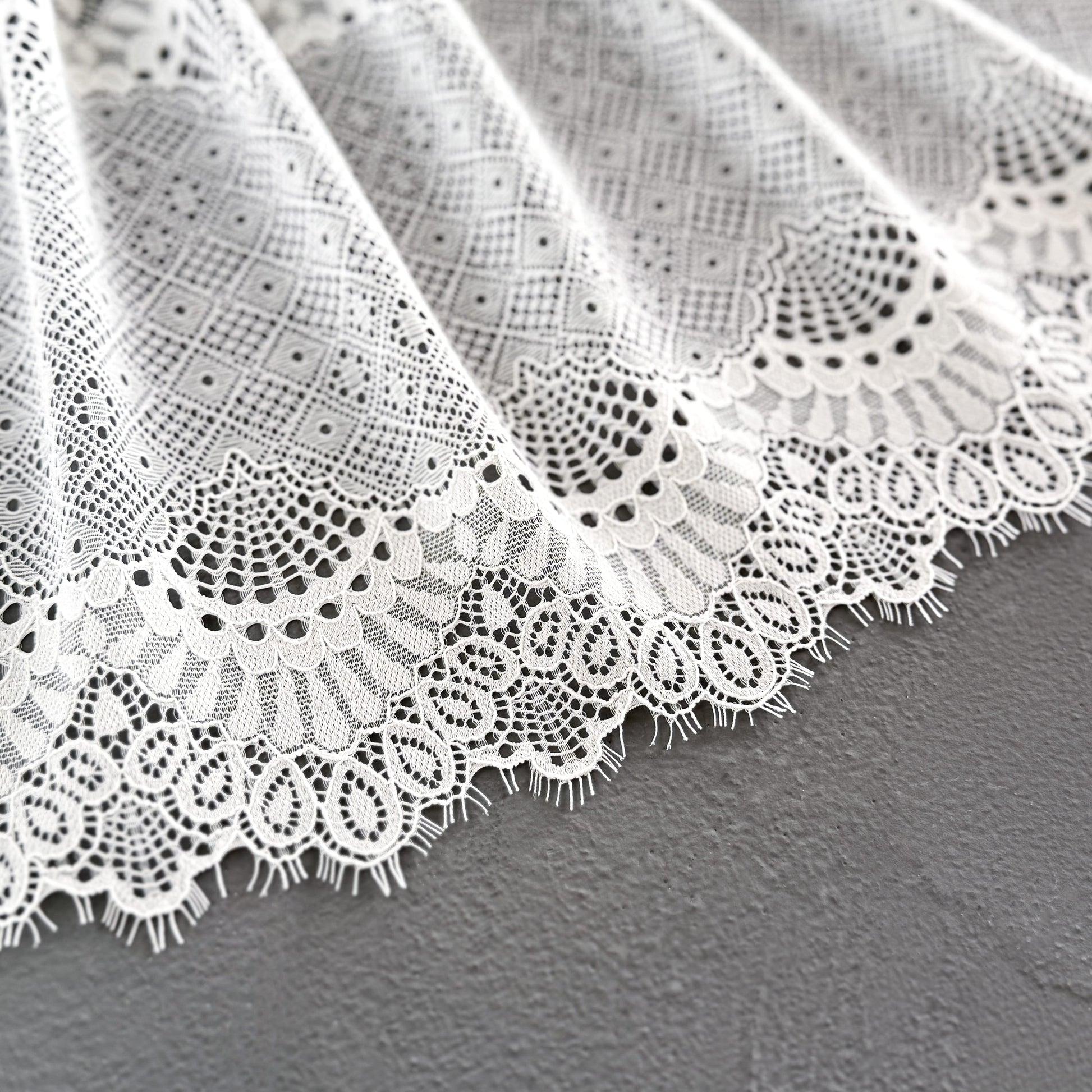 Wide off-white elastic lace fabric with eyelash details, 23 cm wide, highlighting its intricate design and elegant craftsmanship, perfect for intimate apparel.