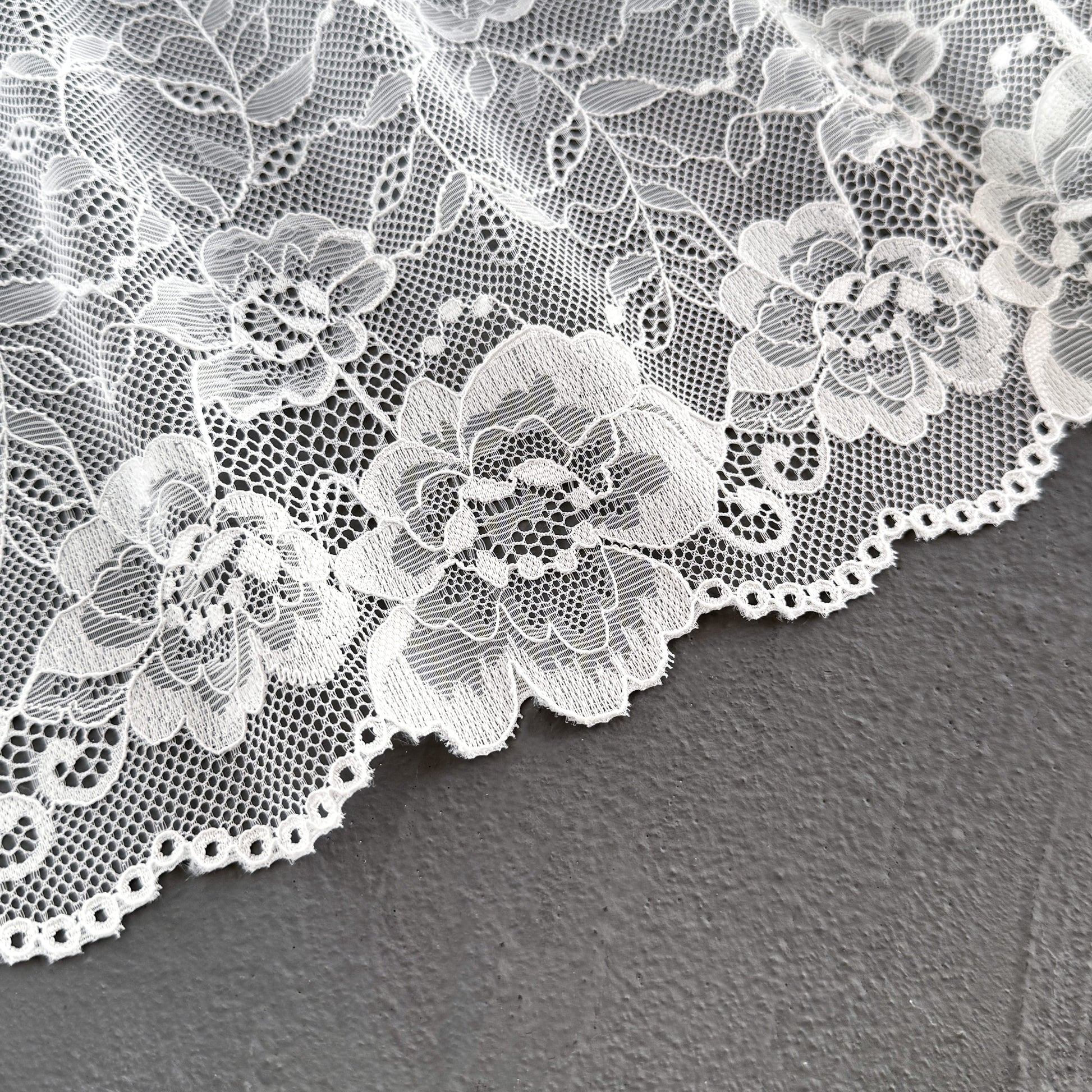 Close-up of off-white elastic lace, 23 cm wide, showcasing detailed floral embroidery