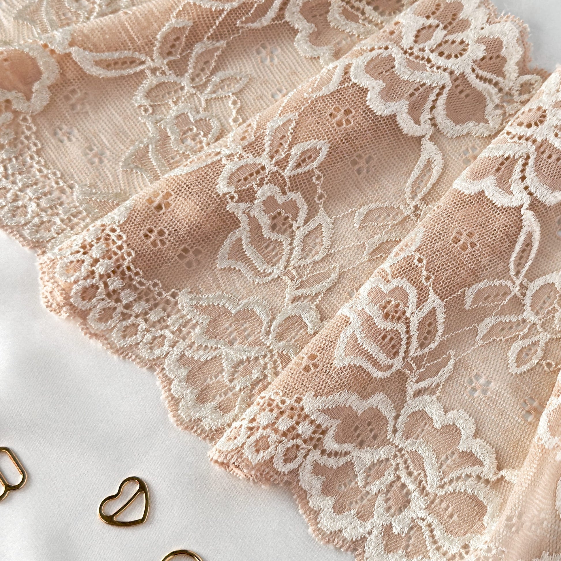 Cold beige elastic lace fabric, 16cm wide, featuring floral design, shown with sewing accessories.