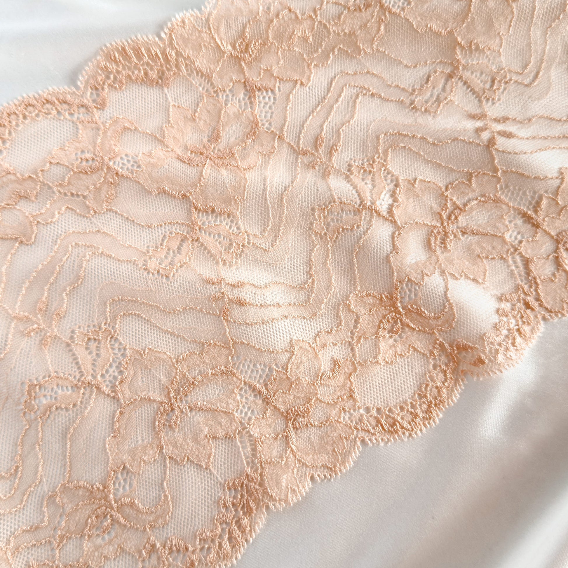 Elegant floral-patterned beige lace trim on satin, perfect for crafting bralettes and underwear.