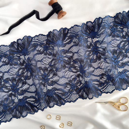 Dark blue elastic lace fabric, 22 cm wide, featuring intricate floral patterns, styled with sewing accessories for lingerie crafting inspiration.