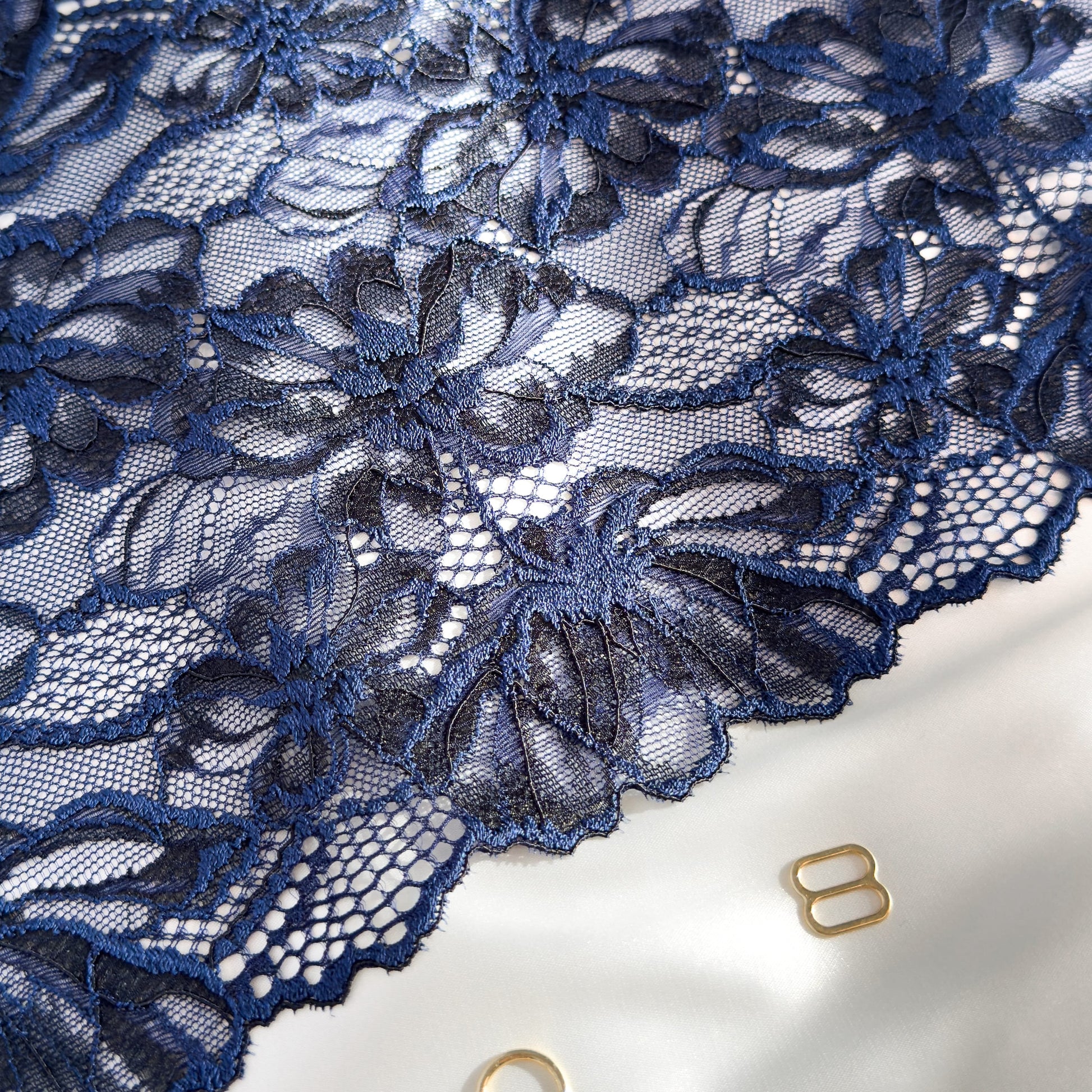 Close-up of dark blue elastic lace trim, 22 cm wide, highlighting its detailed floral design, perfect for elegant lingerie projects.