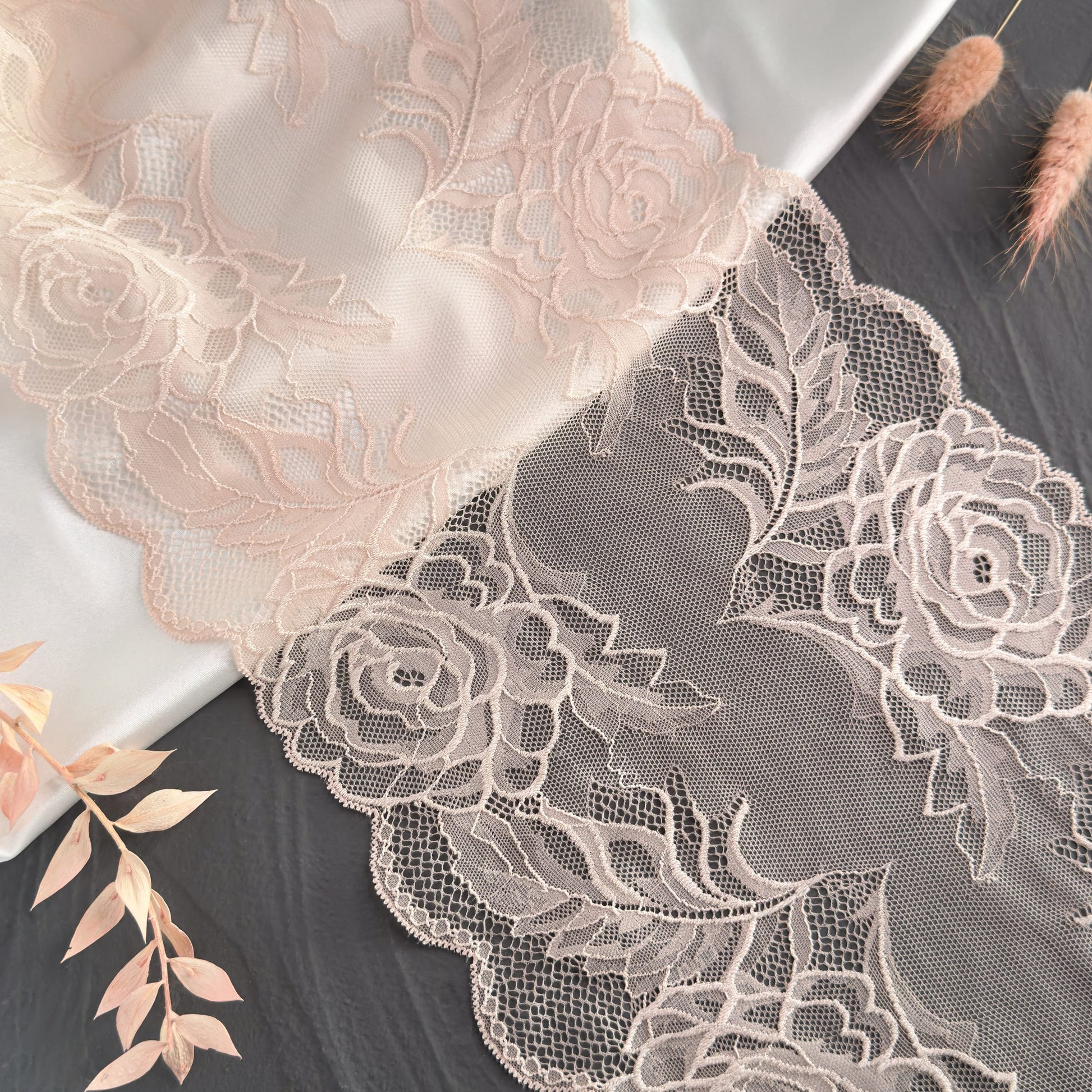 Delicate nude beige stretch lace with rose motifs, displayed on satin, perfect for creating elegant bralettes and panties.