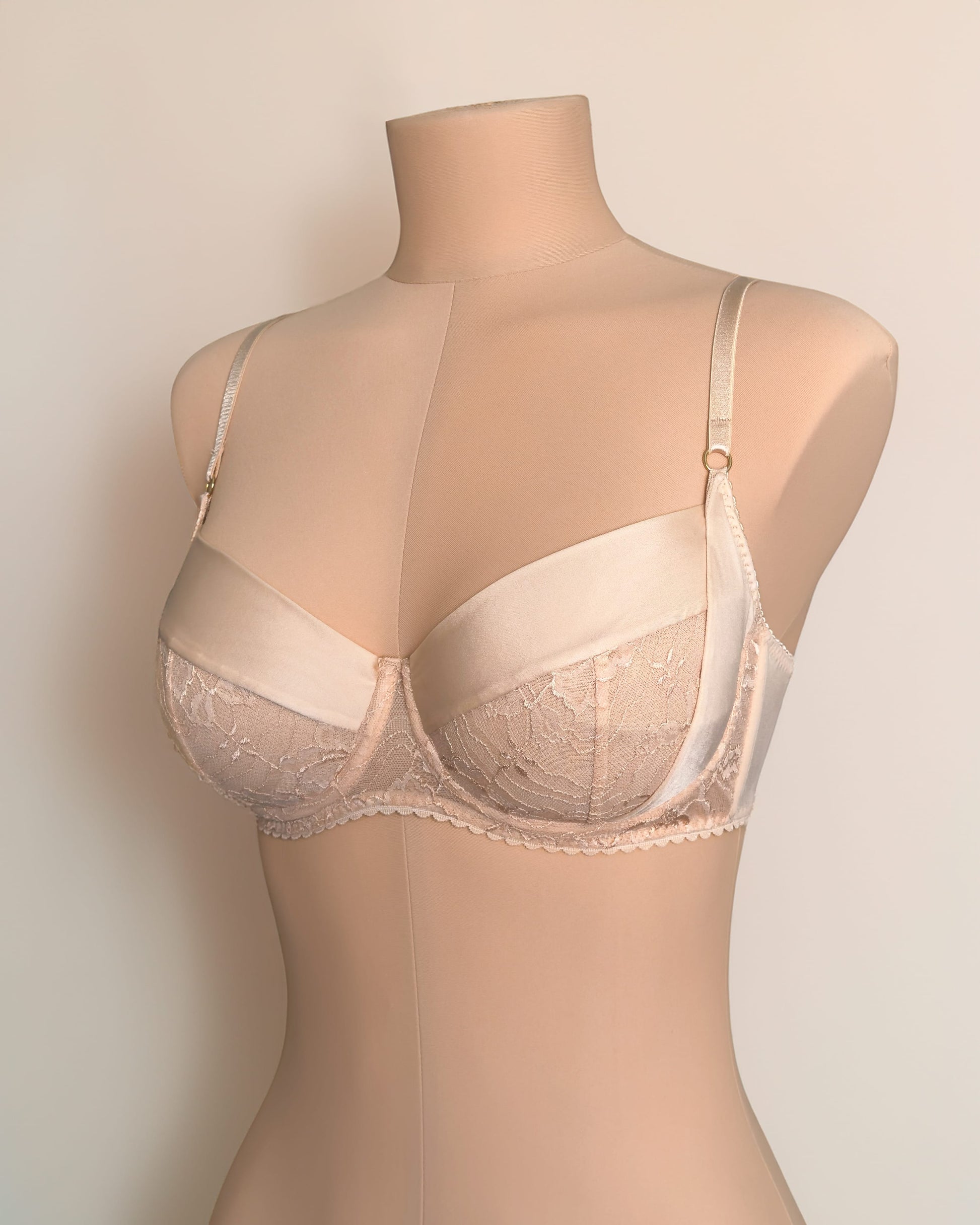 Beige lace bra on mannequin, showcasing delicate floral designs and high-quality fabric for handmade lingerie.