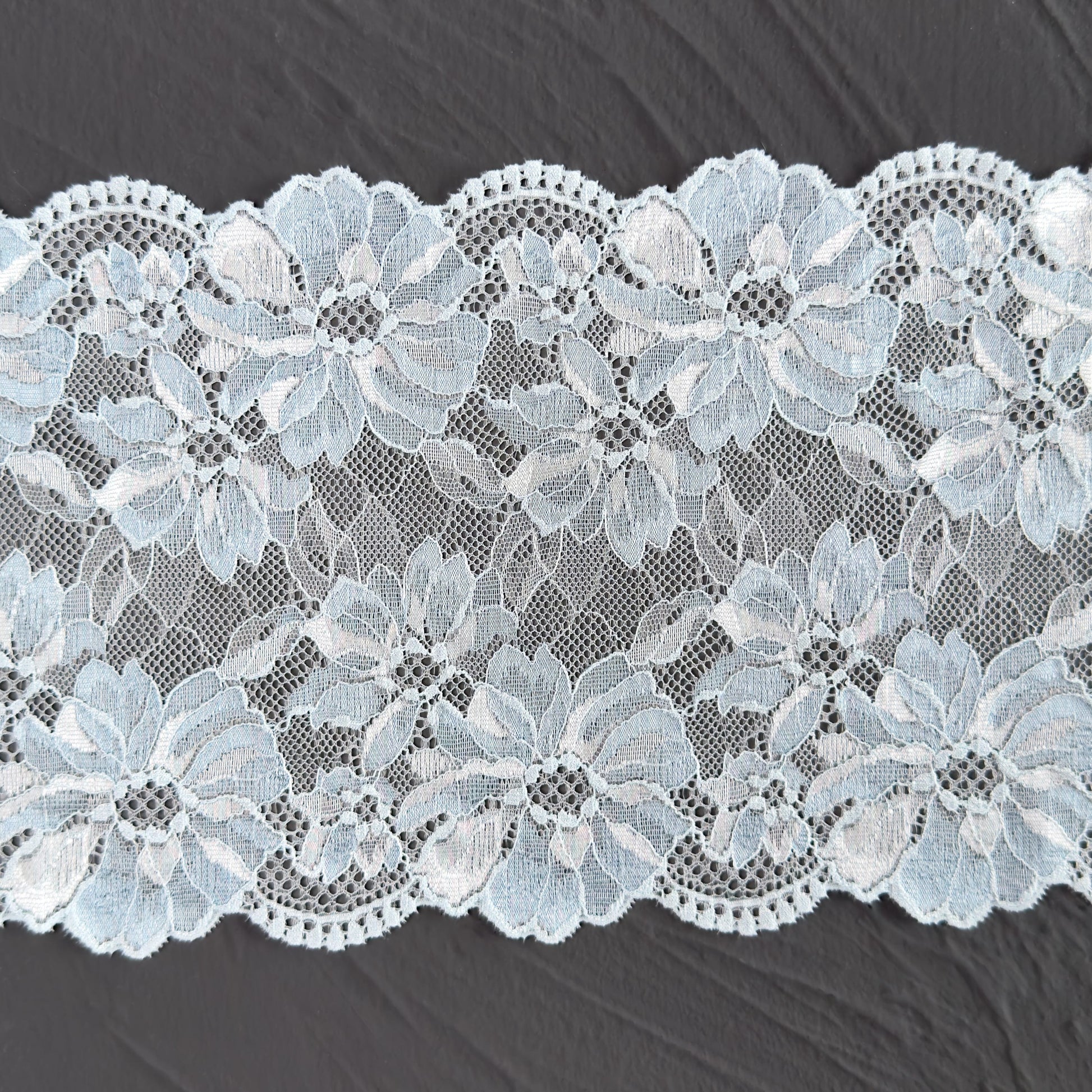 Close-up of light blue elastic lace, 17cm wide, highlighting soft texture and elegant floral embroidery.
