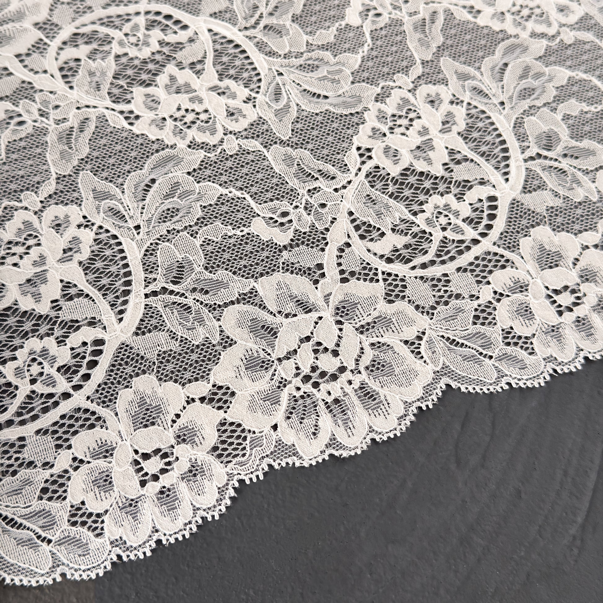 Close-up of white floral lace fabric on a dark background
