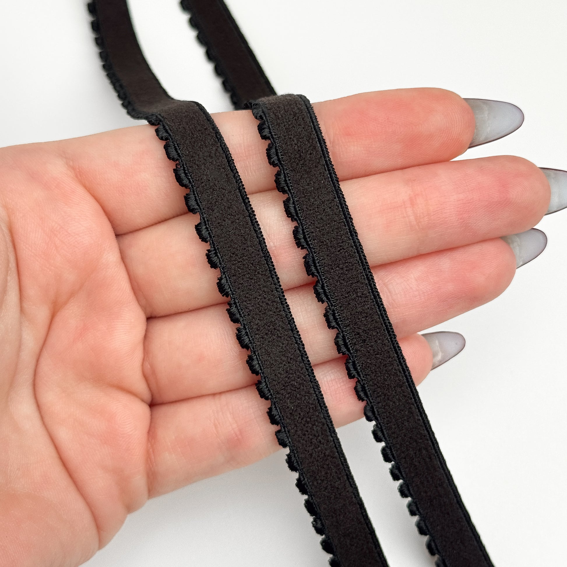 Brown elastic band held between fingers on a white background