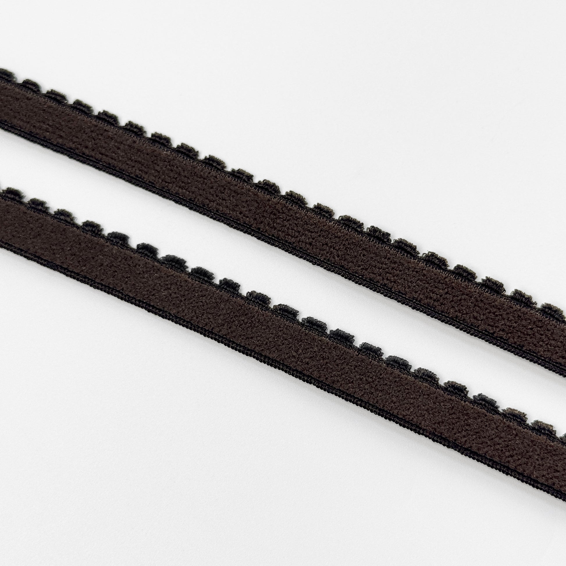 Two brown plush elastics with a zigzag edge on a white background
