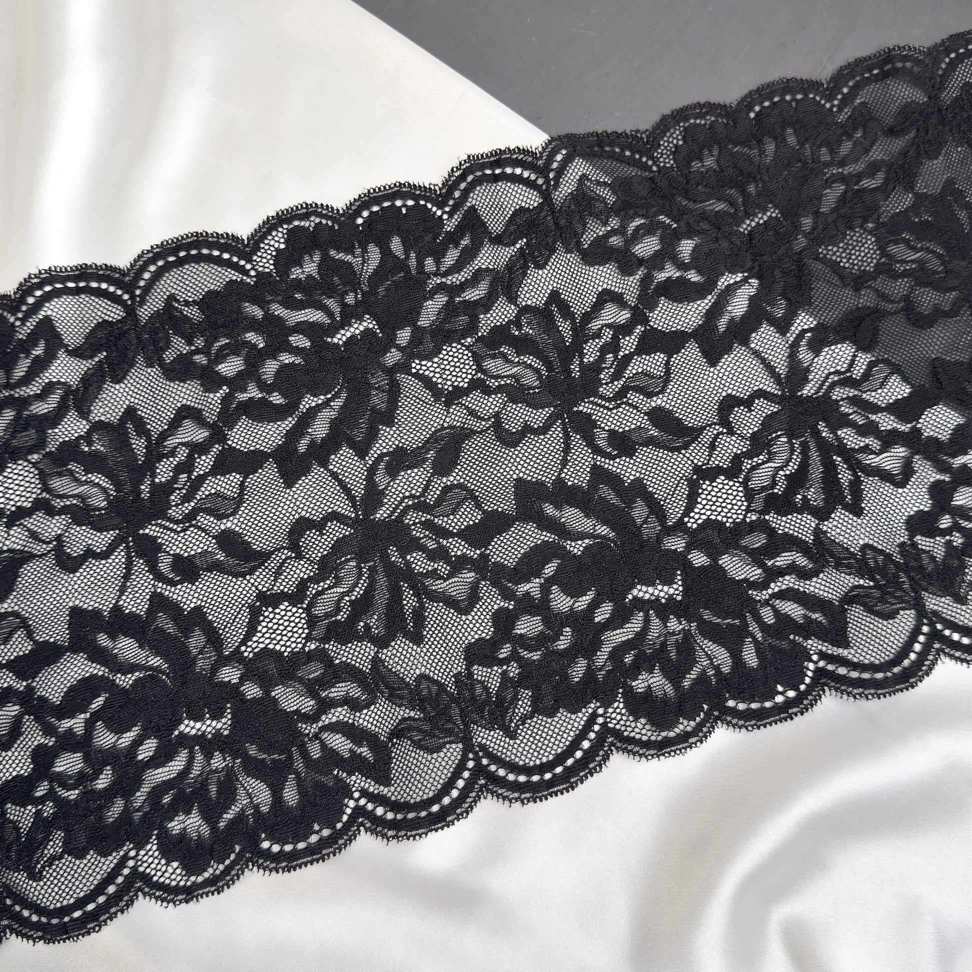 Black lace fabric on a white satin background