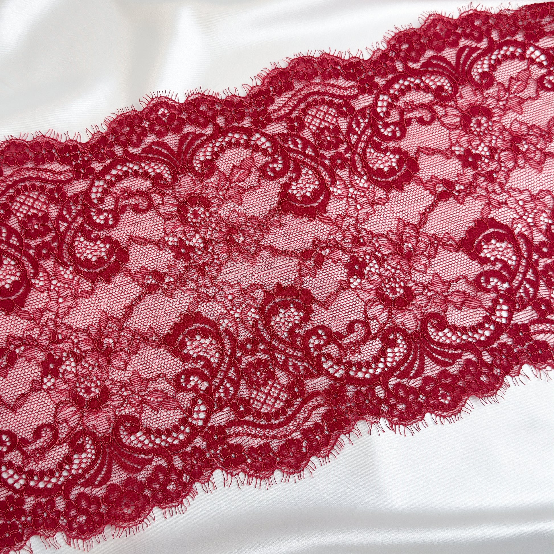 Close-up of dark red lace fabric on a white background